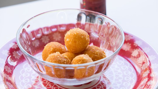 Bolinhas de queijo douradas e crocantes, servidas em travessa.