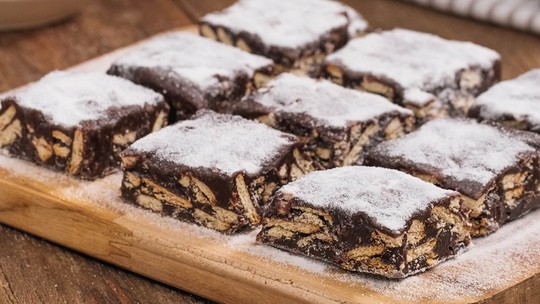 Palha italiana em pedaços quadrados, com biscoitos e chocolate.