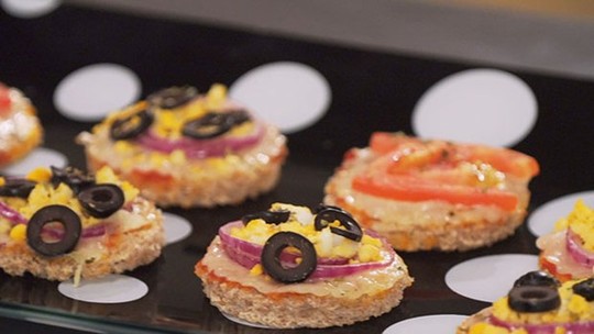 Minipizzas variadas em uma assadeira, prontas para serem servidas.